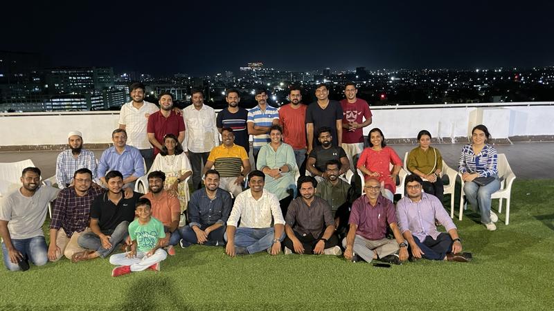 The group seated together on a rooftop lawn at night